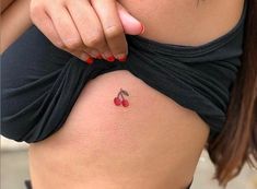 a close up of a woman's stomach with tattoos on her belly and small cherries