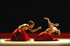 two people in red dresses are performing on the floor with one person upside down and another standing up