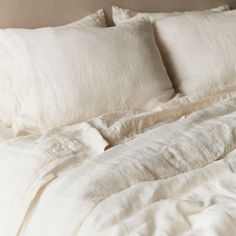 an unmade bed with white linens and pillows