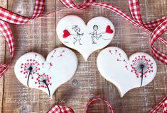 three decorated heart shaped cookies on top of a wooden table