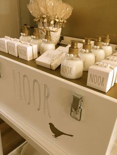 a white dresser topped with lots of personalized items next to a vase filled with flowers