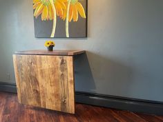 a wooden table sitting in front of a painting on the wall