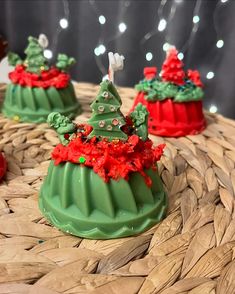 three small green christmas trees sitting on top of a basket