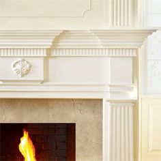 a white fireplace with a fire burning in it's mantle and no one around