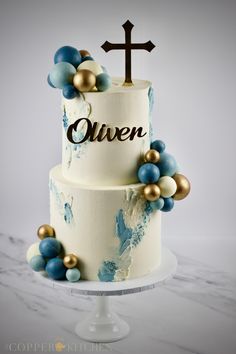 a three tiered cake decorated with blue and gold decorations, including a cross on top