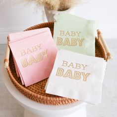 three napkins sitting on top of a white toilet next to a basket with flowers