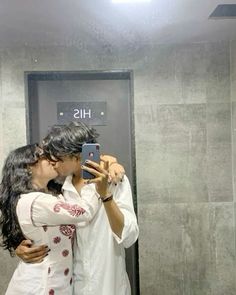 a man and woman taking a selfie in front of a bathroom mirror with their cell phone