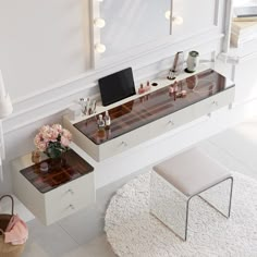 a desk with a laptop and other items on it in front of a wall mounted mirror