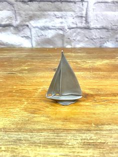 a small metal sailboat sitting on top of a wooden table