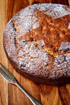 a cake sitting on top of a wooden cutting board next to a knife and fork