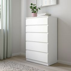 a white chest of drawers with a plant on top