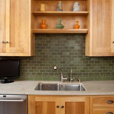 a kitchen with wooden cabinets and green tile backsplash