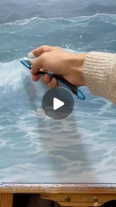 a person holding a cell phone in front of a table with water and waves on it