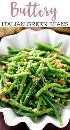 a white bowl filled with green beans on top of a wooden table next to bread