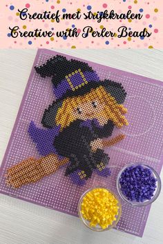 a cross stitch pattern for a witch with her hat and broom on the table next to some beads