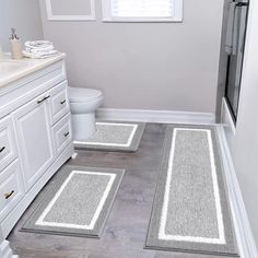 two bathroom rugs on the floor in front of a toilet