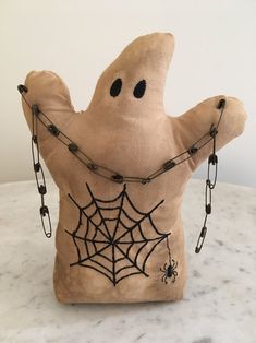 a stuffed ghost with chains around it's neck on a marble counter top in front of a white wall