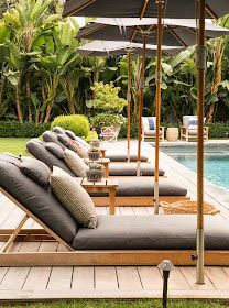 a row of chaise lounges sitting on top of a wooden deck next to a swimming pool