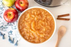 a bowl of oatmeal next to two apples and an instant pressure cooker