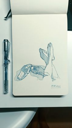 a notebook with a drawing of a woman sitting on a bench next to a fountain pen