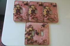 four pink flowered switch plates sitting on top of a white table