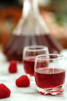 three glasses filled with raspberries on a table