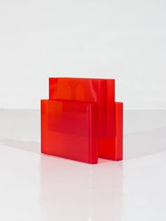 two pieces of red glass sitting on top of a white floor next to each other