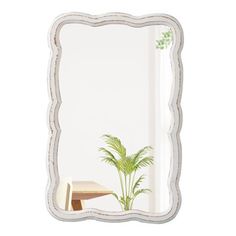 a mirror sitting on top of a wooden table next to a potted palm tree