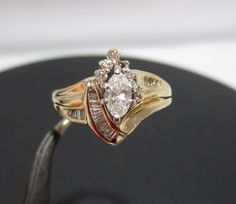 a gold ring with a white diamond on it sitting on top of a black surface