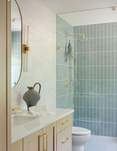 a bathroom with blue tiled walls and white counter tops, gold handles on the sink