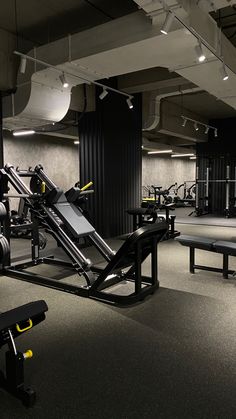 an empty gym with equipment and benches in the foreground, lights on above them