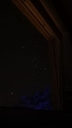 the night sky is lit up with stars in the distance, as seen from an open window