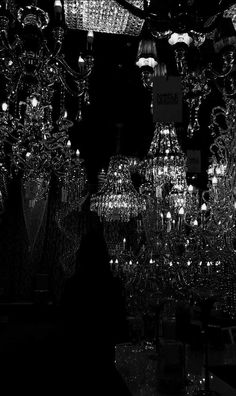 black and white photograph of chandeliers hanging from the ceiling in a dark room