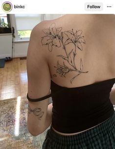 the back of a woman's shoulder with flowers tattooed on her left arm and chest