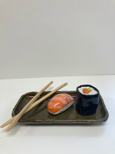 sushi and chopsticks on a green tray with white wall in the background