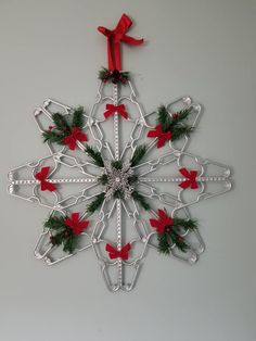 a metal snowflake decorated with red bows and green pineconis on a gray background