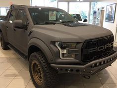 a grey truck is parked in a showroom with other vehicles on display behind it