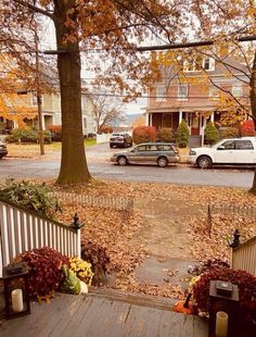 a house with fall leaves on the ground and cars parked in front of it,