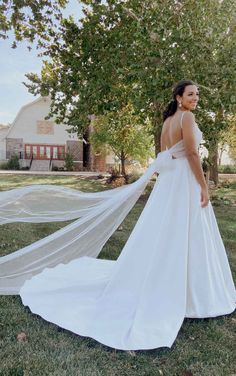 a woman in a white wedding dress is posing for the camera with her veil flying