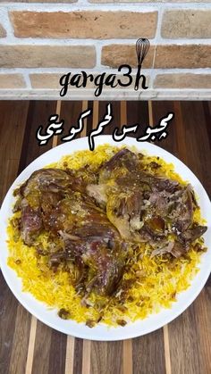 a white plate topped with meat and rice on top of a wooden table next to a brick wall