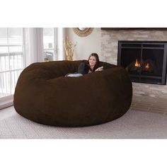 a woman sitting in a large bean bag chair next to a fire place and fireplace