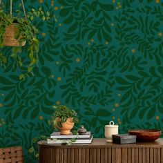 a room with green wallpaper and potted plants on top of a wooden table