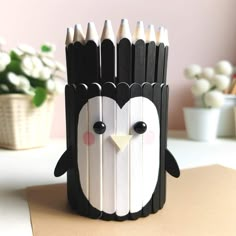 a black and white penguin pencil holder sitting on top of a table