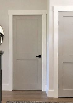 a hallway with two white doors and a mirror on the wall next to an entry way