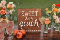 there are peaches and flowers in vases next to a sign that says sweet as a peach