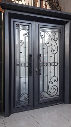 two black doors with intricate iron work on the front and back sides, in an indoor area