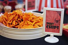 a bowl full of tortilla chips next to a sign that says spidery chips