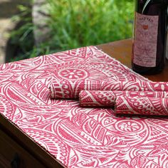 two red napkins sitting on top of a wooden table next to bottles of wine