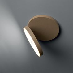 a light that is on the wall next to a gray surface with an oval shape