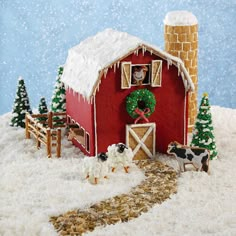 a red barn with snow falling on the roof and sheep in front of it, surrounded by trees